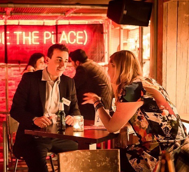 Zwei Menschen im Gespräch an einem Tisch in einer Bar